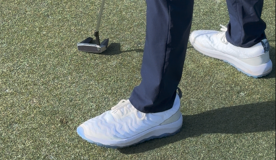 A man wearing FHADE hybrid golf shoes while on the putting green.