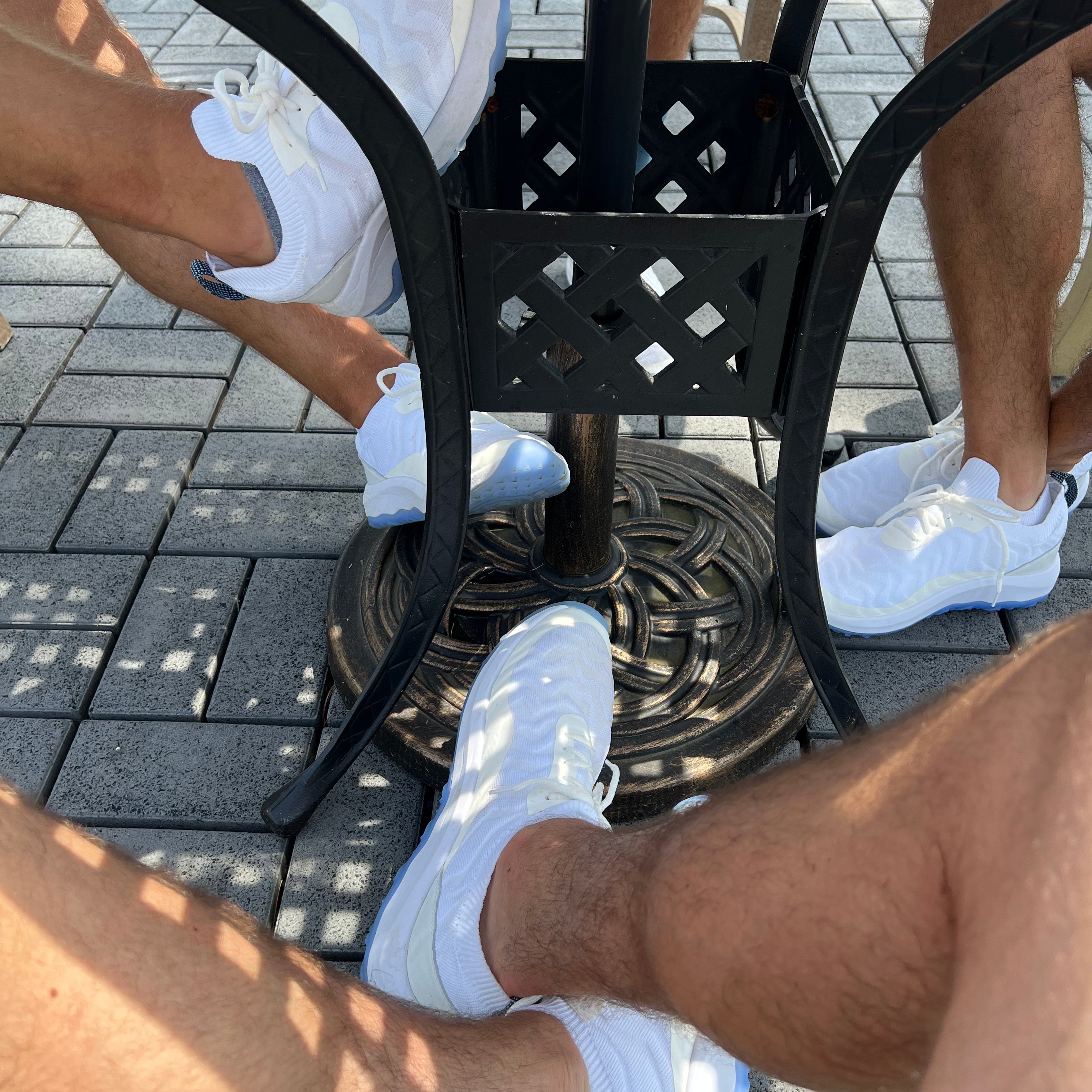 A zoomed in photo of three people's feet all wearing FHADE hybrid golf shoes. 