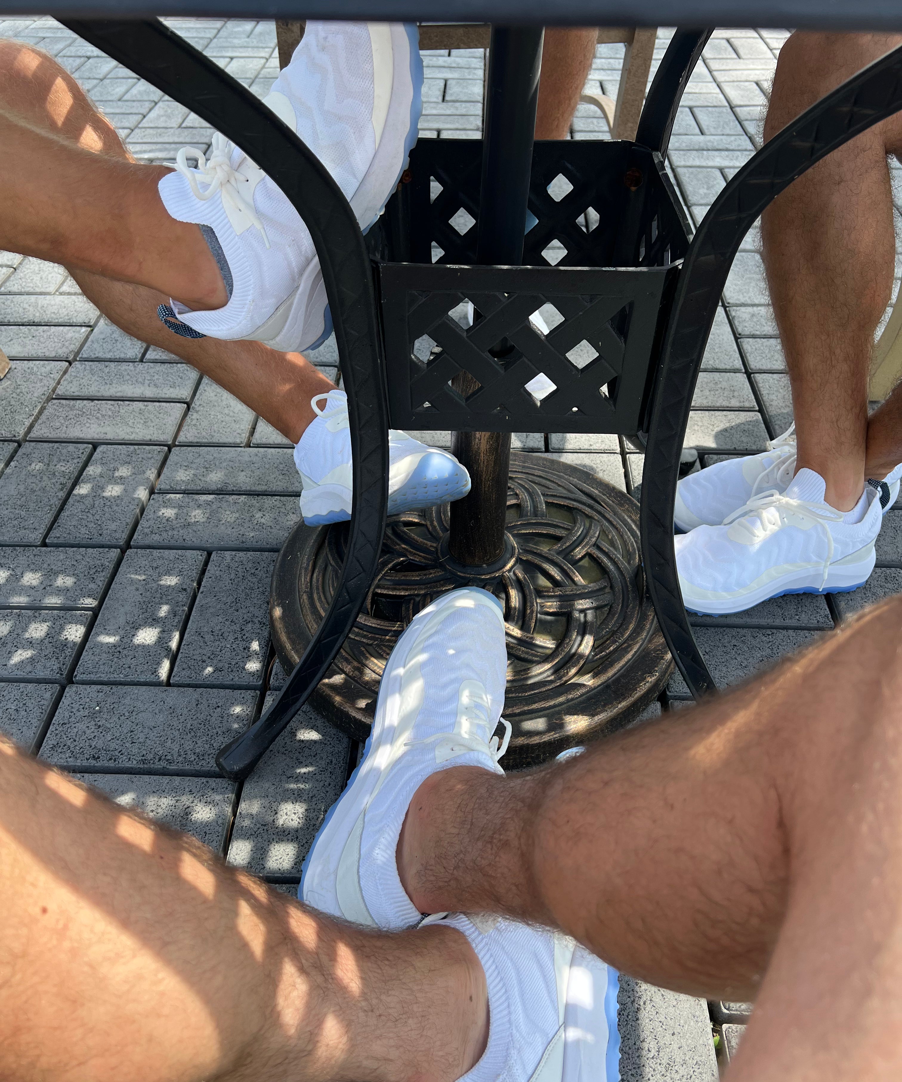 A zoomed in photo of three people's feet all wearing FHADE hybrid golf shoes. 